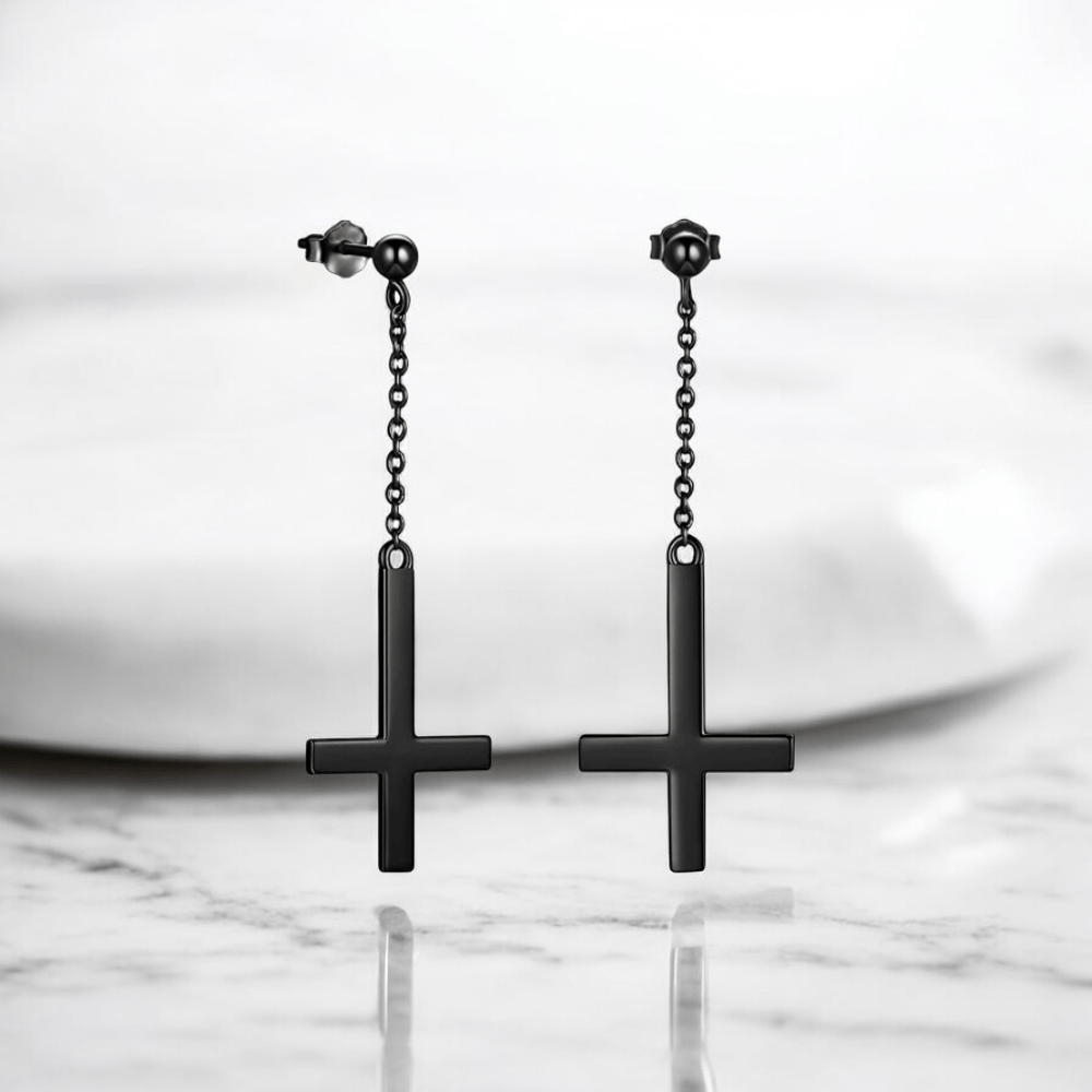 Paire de boucles d'oreilles pendantes noires pour homme avec croix inversée stylisée.