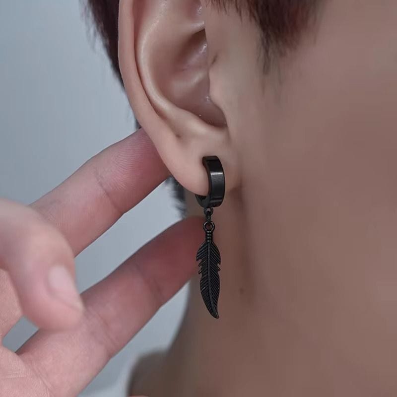 Gros plan sur une boucle d'oreille en acier inoxydable noir, fermoir anneau et pendentif plume