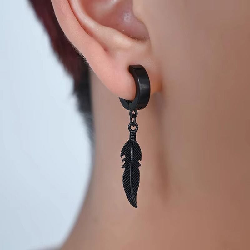 Homme portant une boucle d’oreille pendante en acier inoxydable noir, avec un pendentif en forme de plume détaillée. Style tendance et masculin