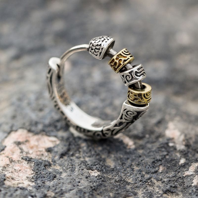 Zoom sur une boucle d’oreille anneau viking en argent vieilli avec perles dorées et argentées gravées.