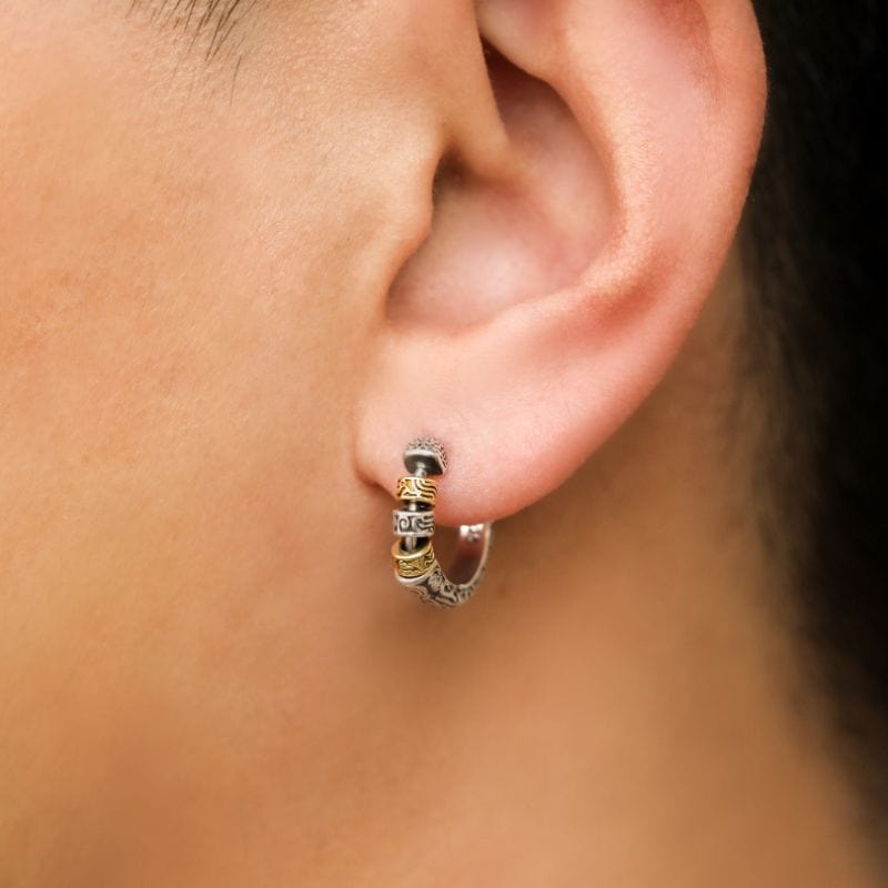 Boucle d’oreille viking anneau portée par un homme, mettant en avant les détails sculptés et les perles dorées