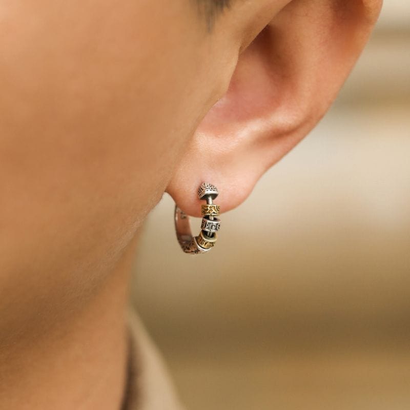 Boucle d'oreille viking pour homme portée à l'oreille, mettant en valeur son design travaillé avec gravures et perles en relief