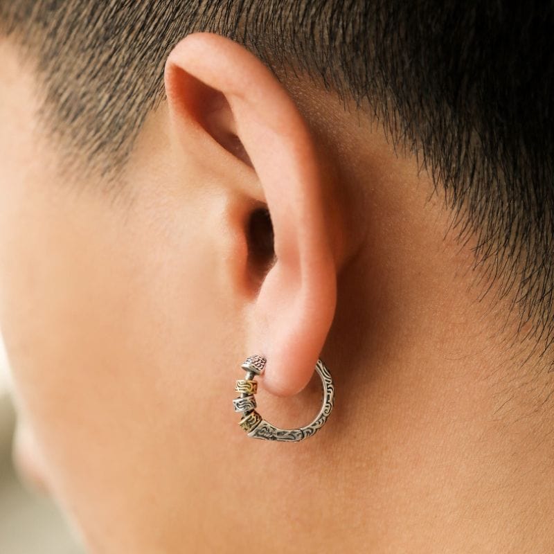 Boucle d’oreille anneau viking portée sur une oreille masculine, mettant en valeur le design détaillé et le fermoir discret