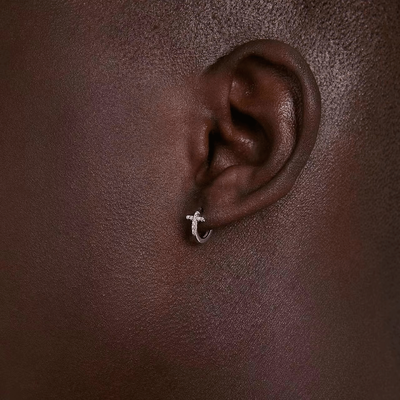 Boucle d’oreille homme pendante en argent 925, anneau et croix diamantée portée sur oreille masculine, gros plan
