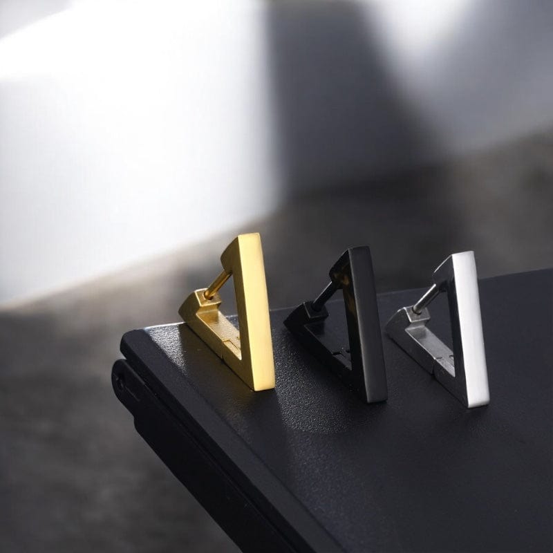 Boucles d’oreilles minimalistes pour homme – Présentation des trois coloris debout sur une surface noire.