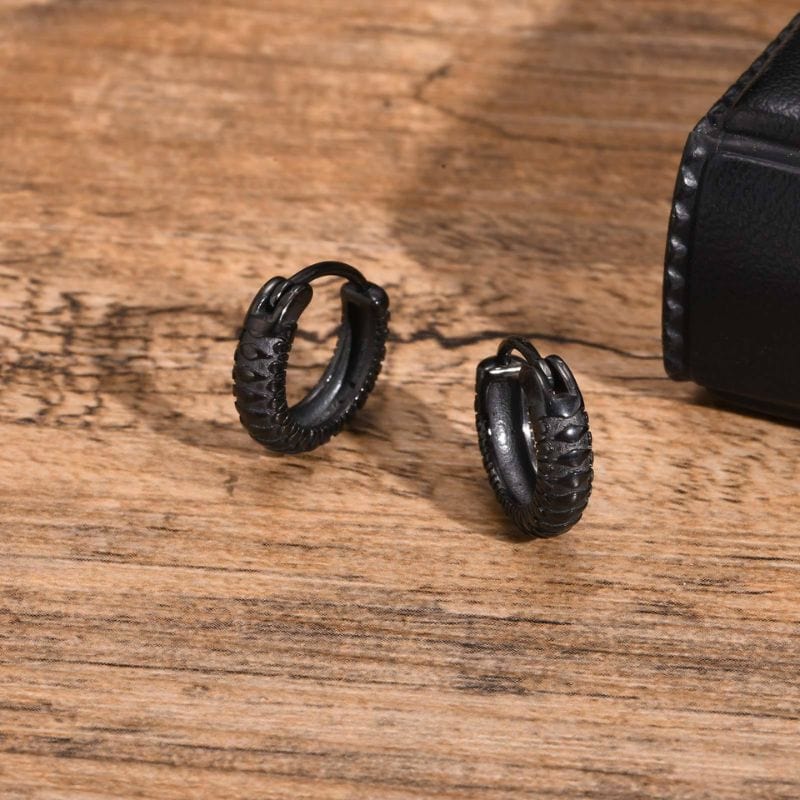 Deux boucles d’oreilles pour homme en acier inoxydable noir, style créoles, à motifs texturés. Bijoux masculins modernes idéals pour un look élégant et affirmé