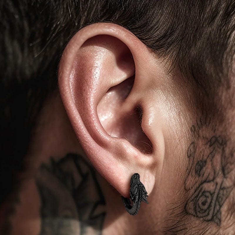 Boucle d’oreille dragon noire portée par un homme avec tatouage