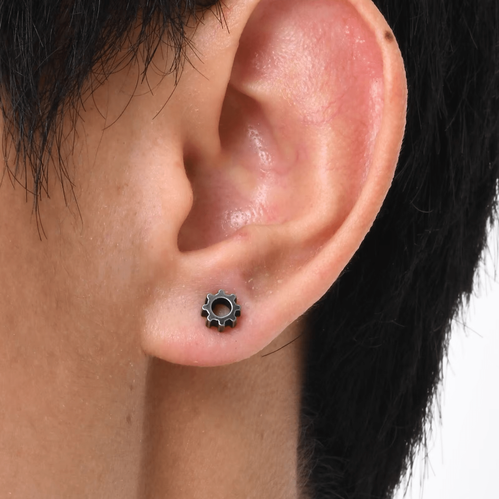 Boucle d'oreille homme engrenage en acier noir portée sur le lobe