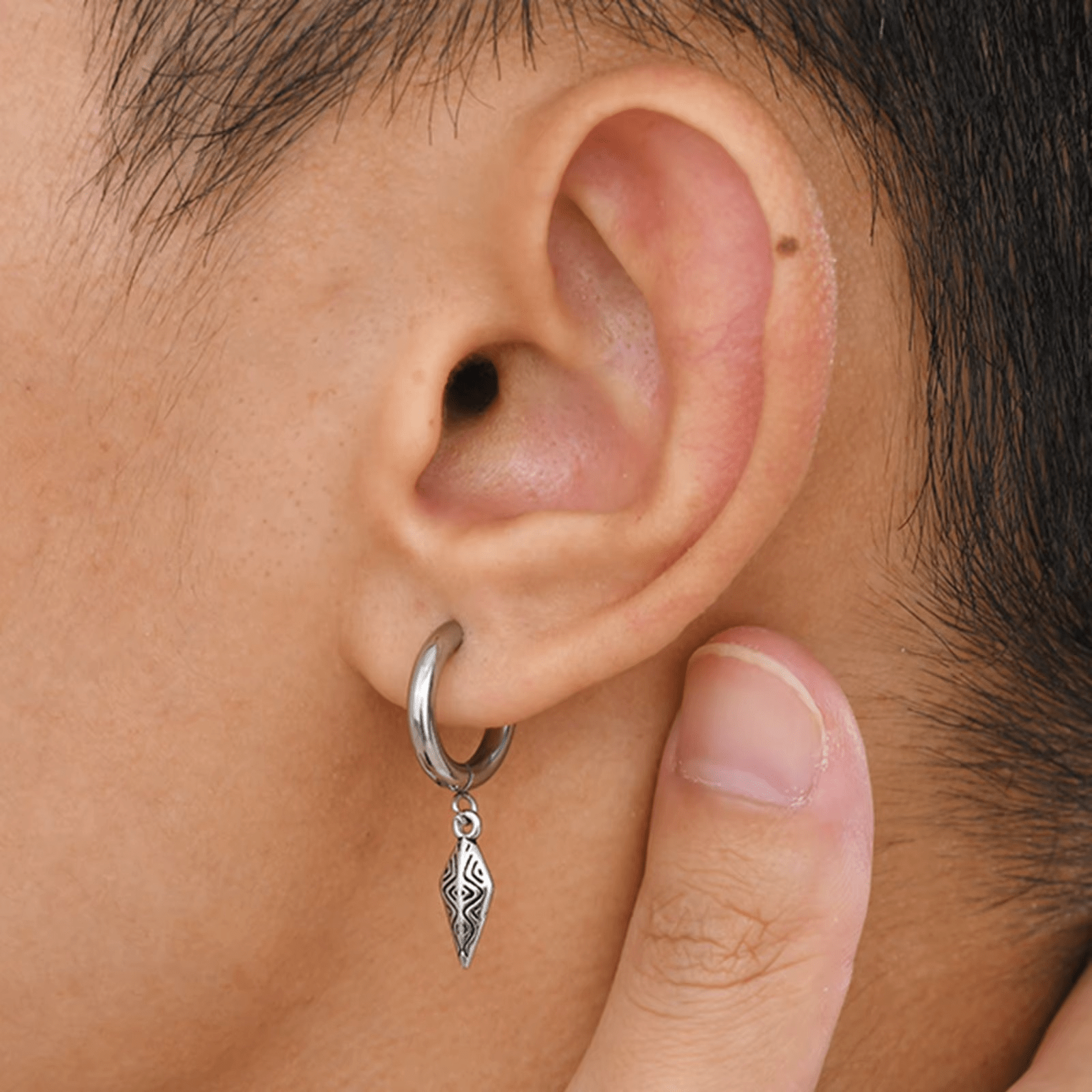 Boucle d’oreille pendante pour homme en acier argenté avec pendentif tribal portée à l’oreille