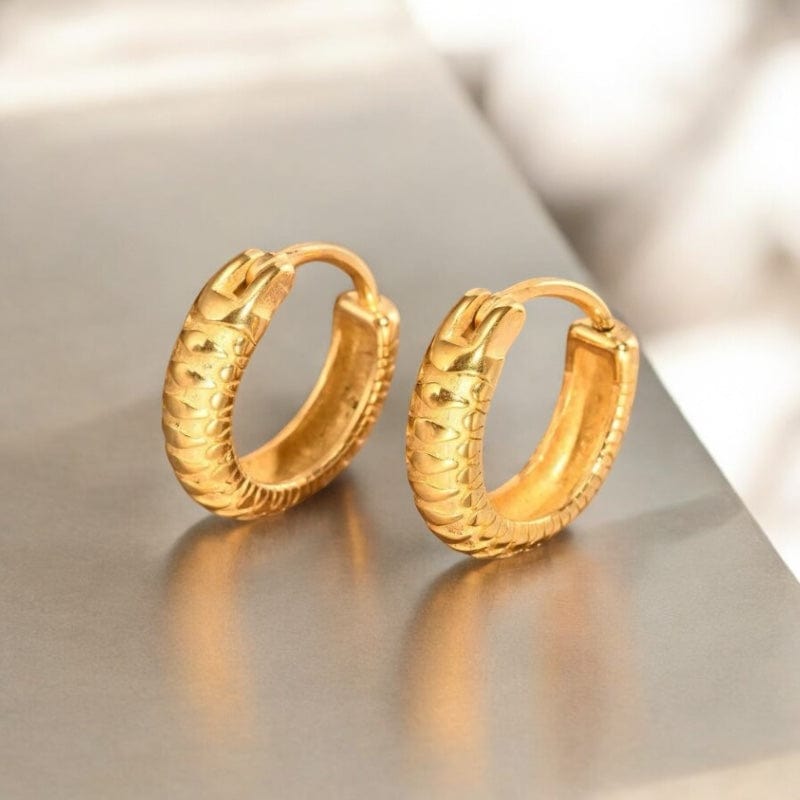 Boucles d'oreilles anneaux dorées en acier inoxydable texturé portées par un homme et tenues à la main pour illustrer la taille réelle et la finition détaillée