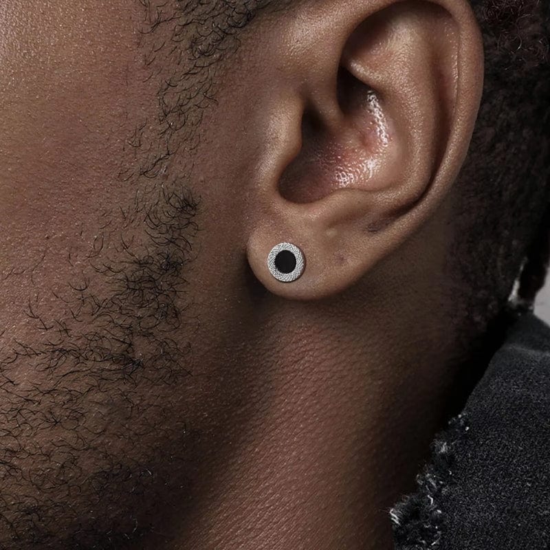 Zoom sur une oreille portant une boucle d’oreille clou homme cercle noir avec texture argentée
