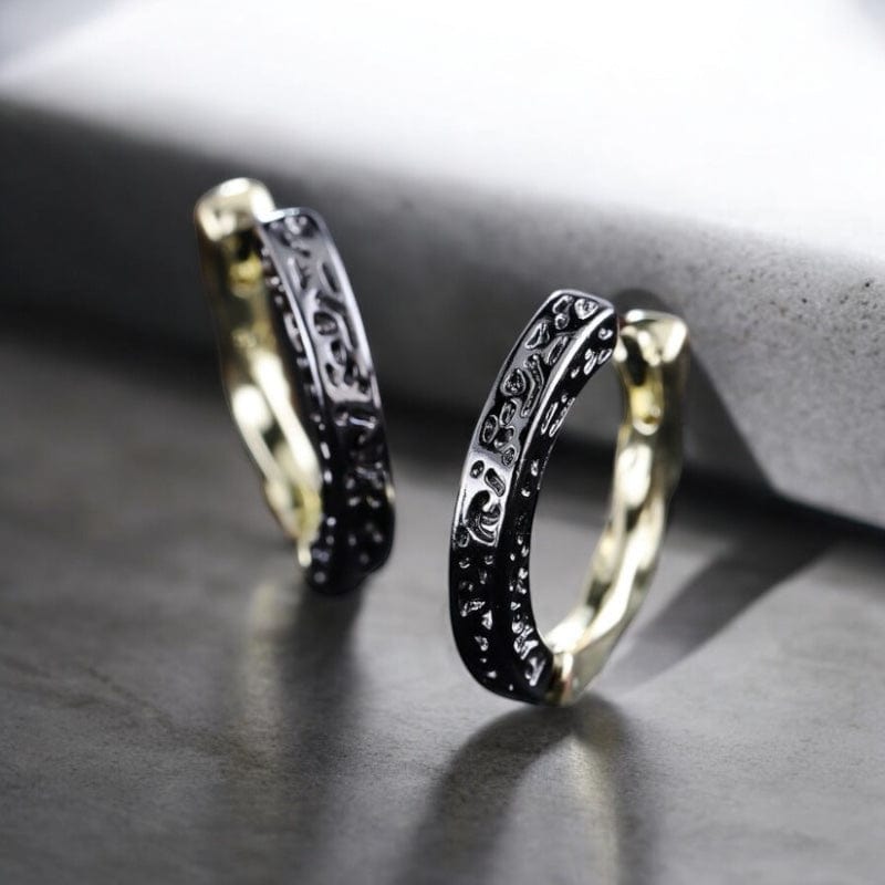 Paire d'anneaux pour homme à la finition bicolore raffinée avec extérieur noir texturé et intérieur doré brillant. Design élégant soulignant une esthétique moderne et audacieuse