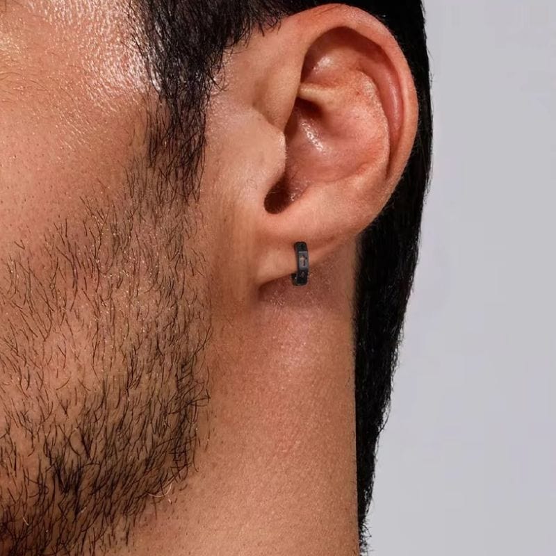 Anneau d’oreille noir pour homme avec croix découpée – vue rapprochée à l’oreille.