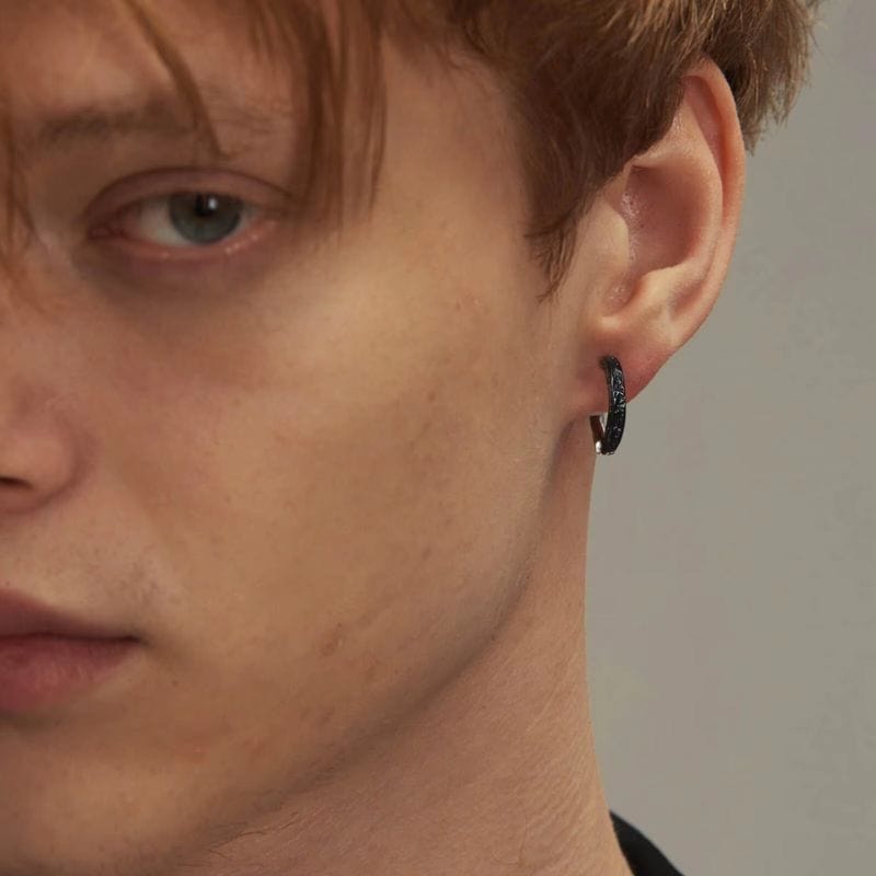 boucle d'oreille créole homme acier inoxydable et argent plaqué noir portée par un homme élégant aux cheveux châtain. Design sobre et masculin adapté à un style contemporain et affirmé