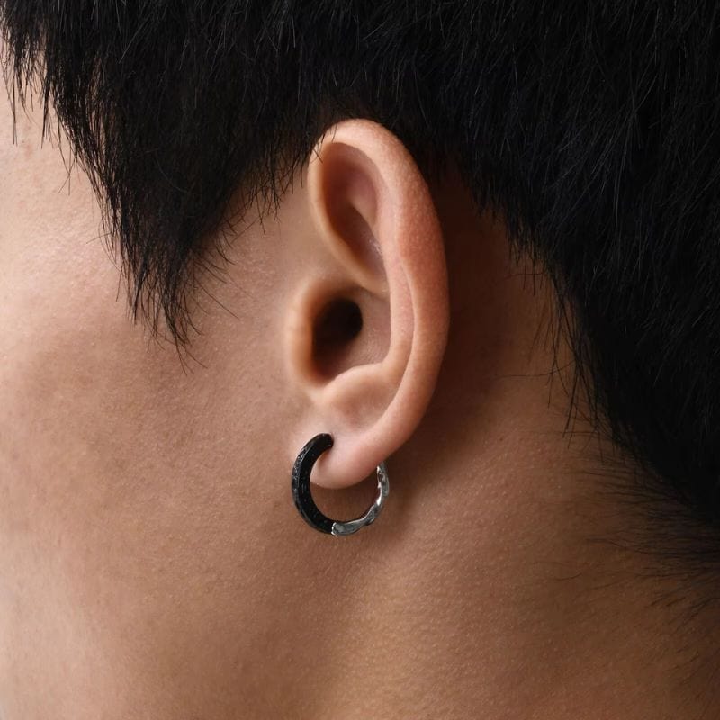 Boucle d’oreille anneau homme en argent plaqué noir et argent brillant, avec motifs texturés discrets, portée à l'oreille. Bijou moderne et élégant pour homme.