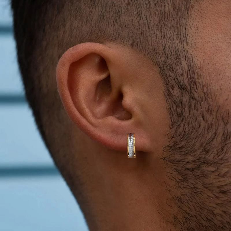 Homme à la barbe fine portant une créole dorée avec gravure plume argentée