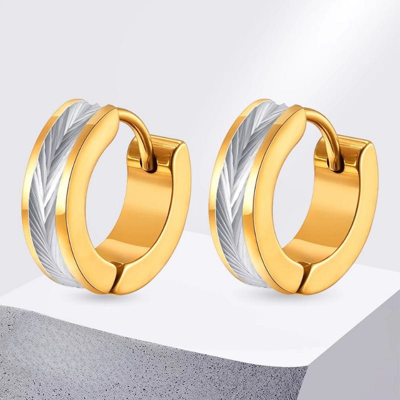 Gros plan de deux créoles dorées avec motif plume sur fond neutre