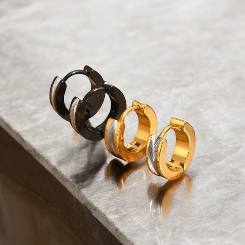 Paire de créoles en acier inoxydable noir et doré posées sur fond en bois