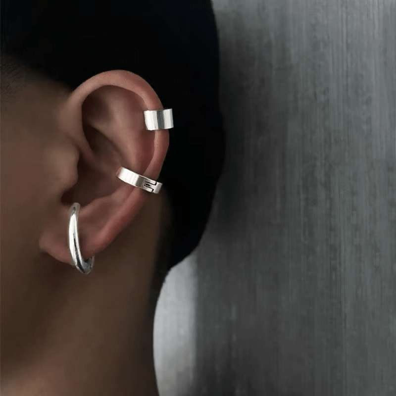 Boucles d'oreilles clips et ear cuffs argentés portés sur une oreille masculine, look urbain et tendance