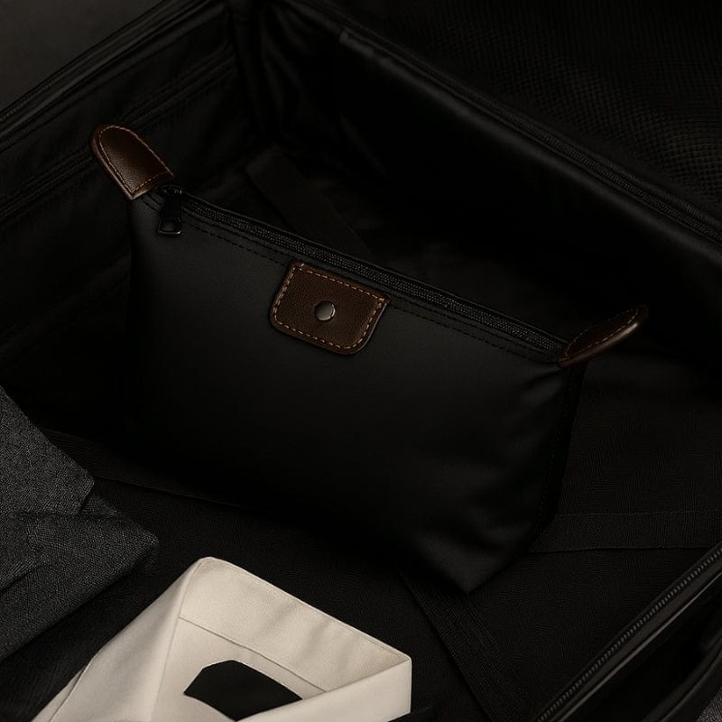 Trousse de toilette noire compacte placée dans une valise homme, format voyage