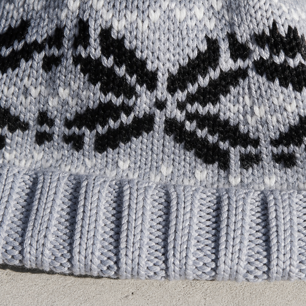 Détail de la maille jacquard à flocons et du revers côtelé du bonnet gris
