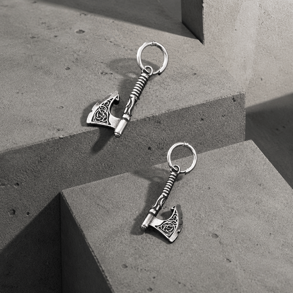 Boucles d'oreilles homme en acier inoxydable avec pendentif hache viking, posées sur des blocs de béton