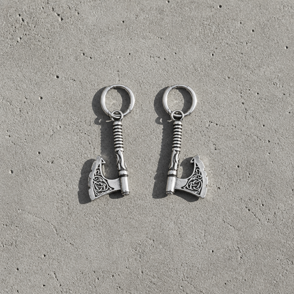 La paire de boucles d'oreilles hache viking en acier inoxydable vue de dessus sur une dalle de béton