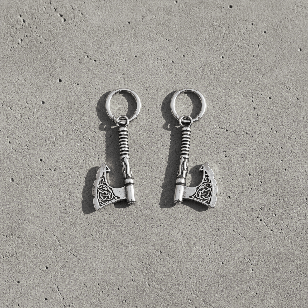 La paire de boucles d'oreilles hache viking en acier inoxydable vue de dessus sur une dalle de béton