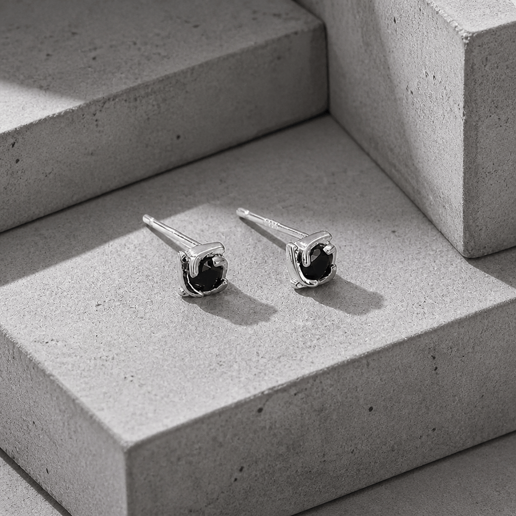 Boucles d'oreilles homme diamant noir en argent 925, vue trois quarts sur béton