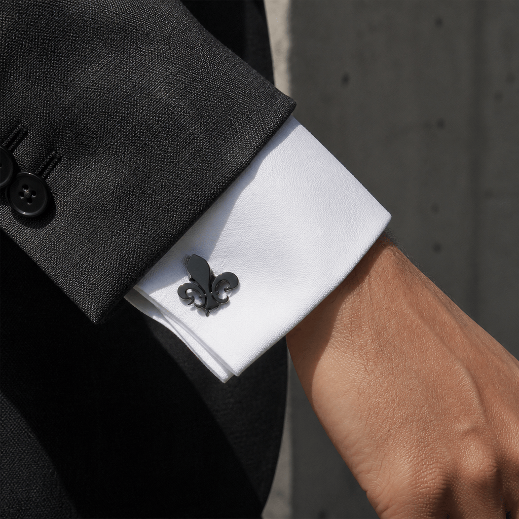 Homme portant un bouton de manchette fleur de lys noir sur une chemise à poignets mousquetaire
