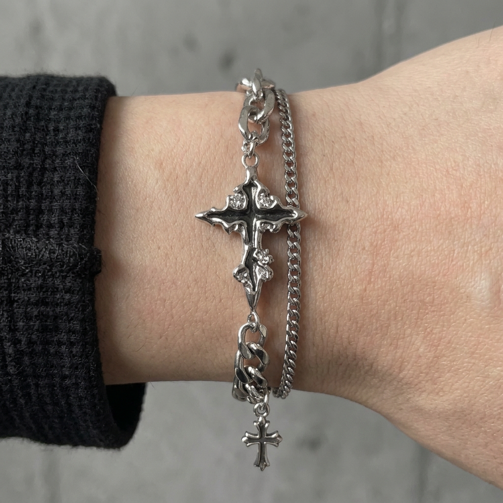 Bracelet double chaîne porté, croix centrale et breloque en acier argenté sur le poignet
