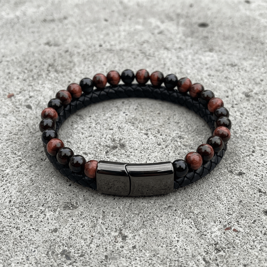 Bracelet homme perles d'œil de taureau et cuir tressé noir posé sur du béton