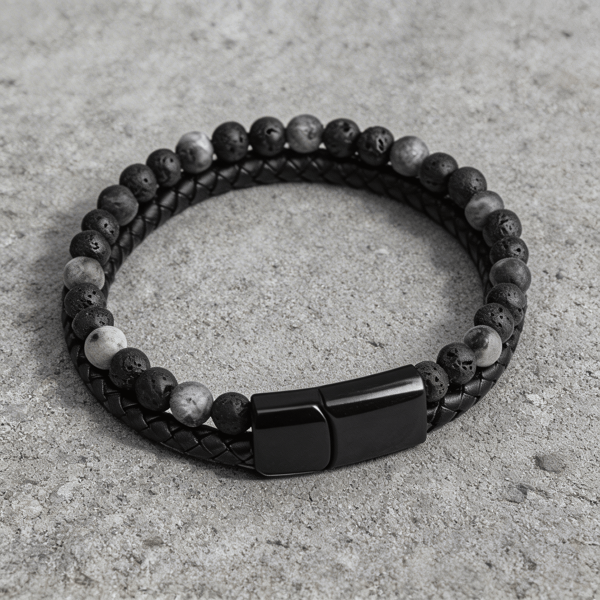Bracelet homme perles de pierre de lave et cuir tressé noir posé sur du béton