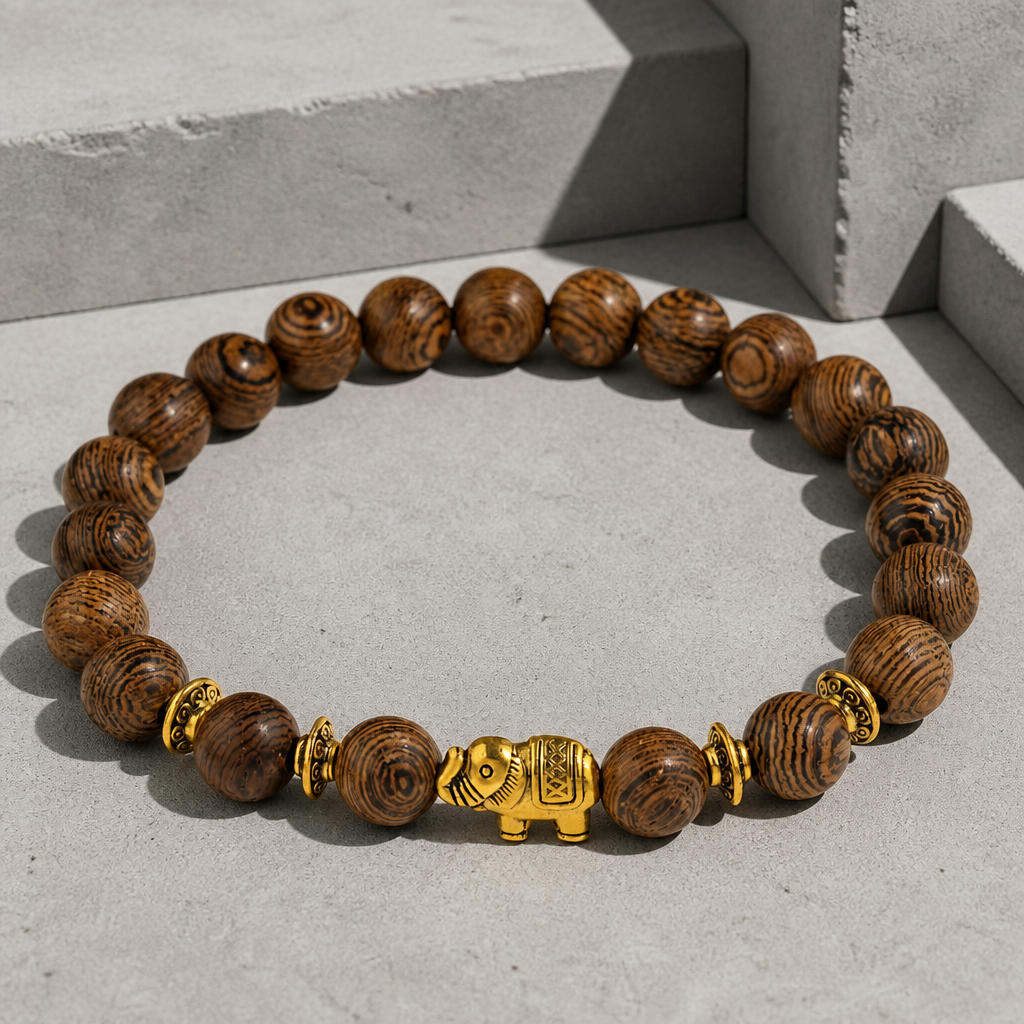 Bracelet été homme en perles de bois, éléphant doré au centre, packshot sur béton clair