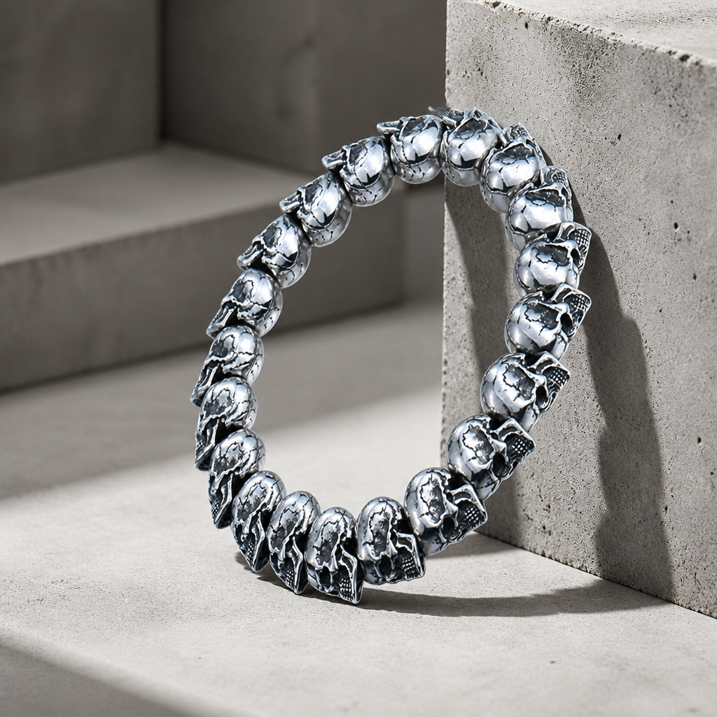 Bracelet gothique homme, rang de crânes argentés appuyé contre un bloc de béton
