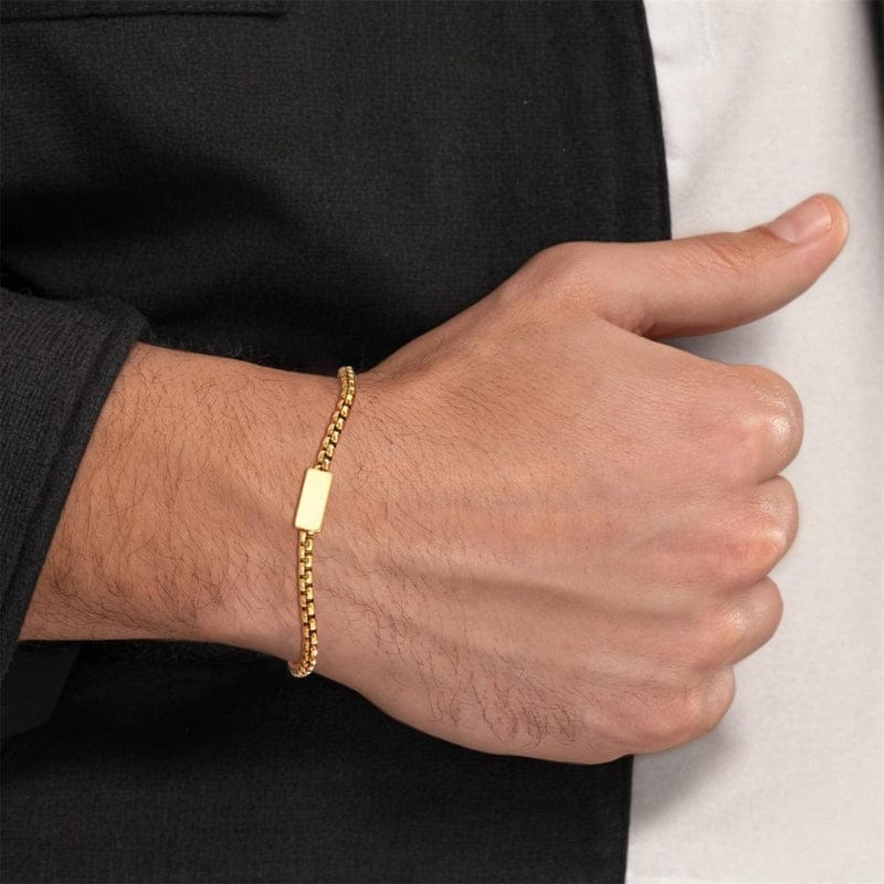 Bracelet homme chaîne fine dorée portée sous une manche de chemise