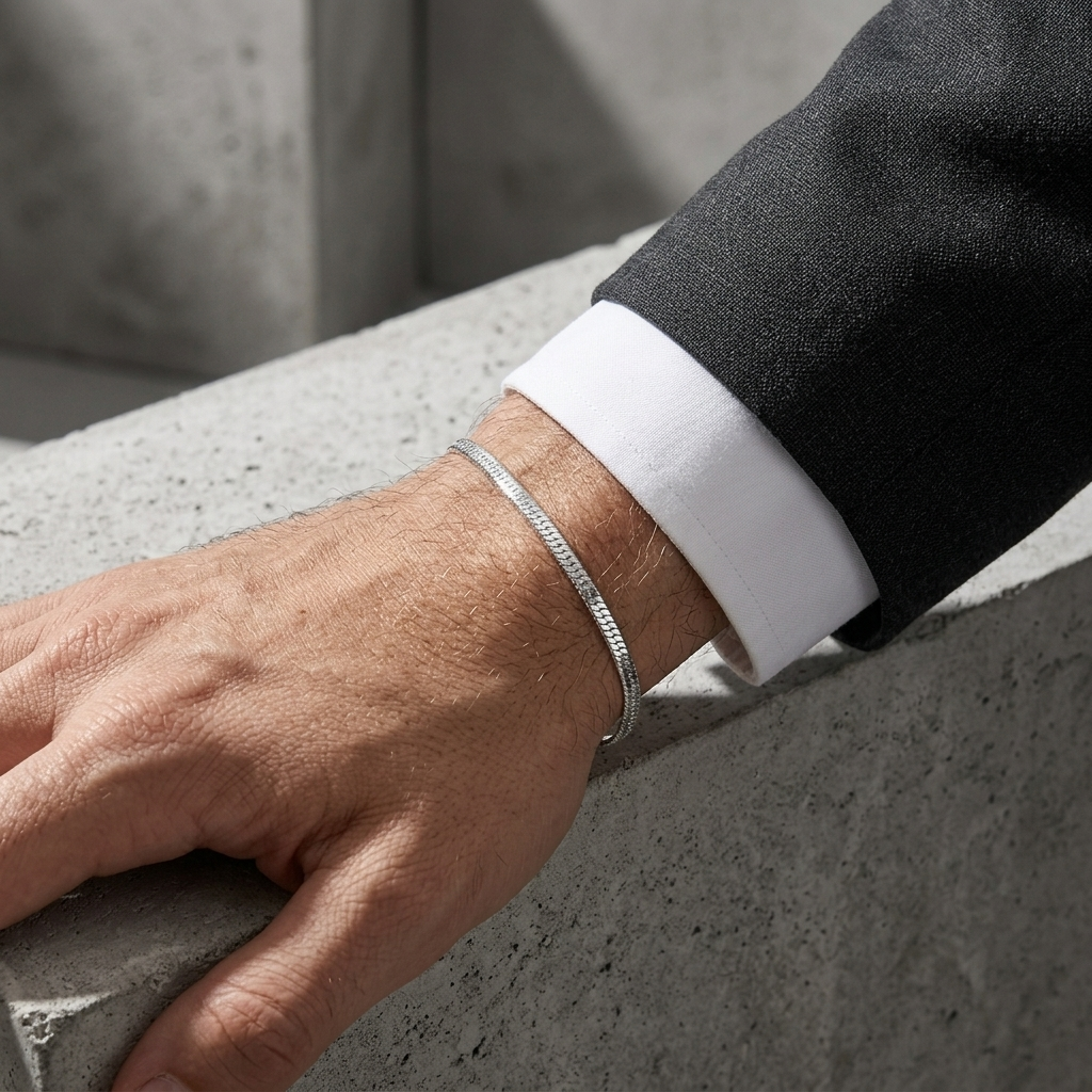 Bracelet argent fin porté sous un poignet de chemise blanche et une manche de costume