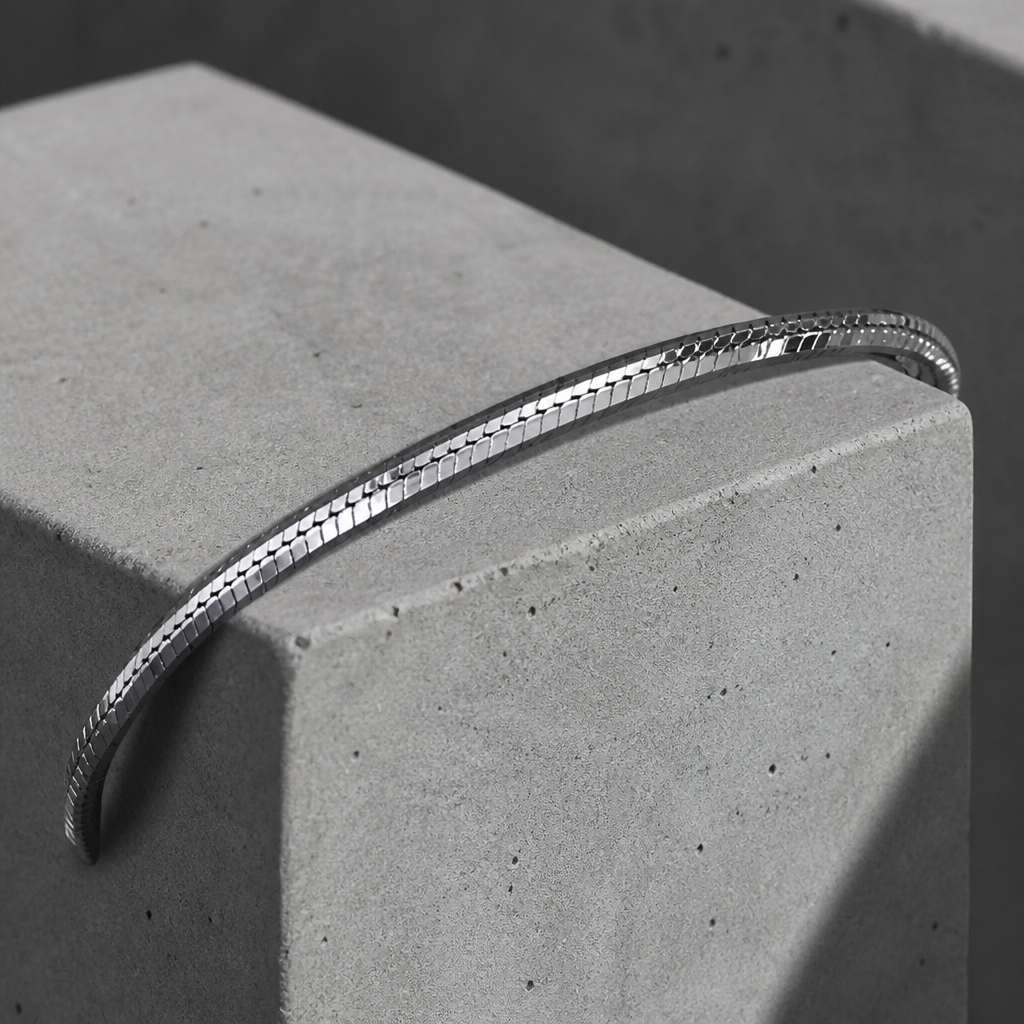 Bracelet en argent drapé sur l'arête d'un bloc de béton clair