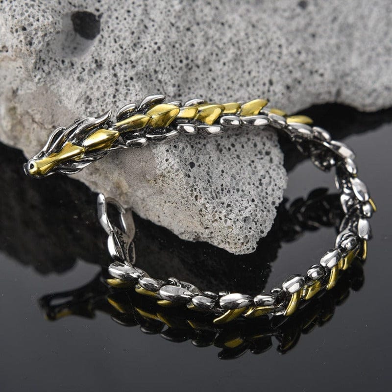 Bracelet dragon homme argent et or posé sur une pierre brute