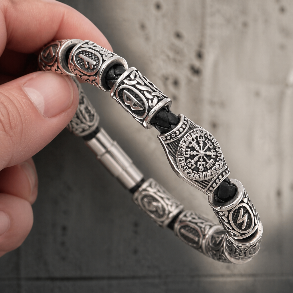 Bracelet viking argent tenu à la main, compas runique visible au centre de la rangée