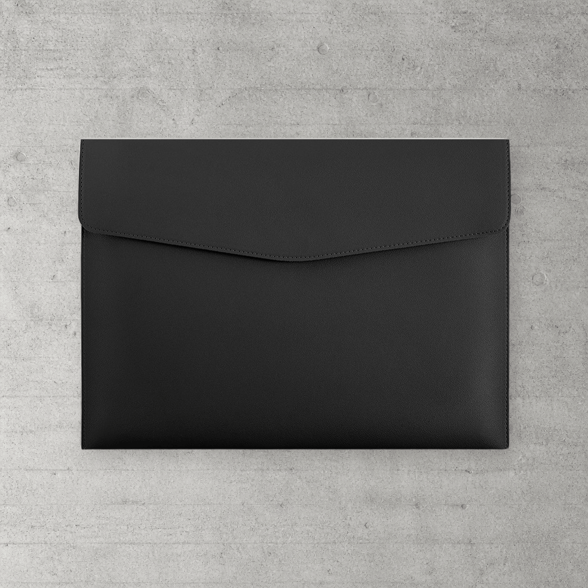 Chemise porte-document A4 en simili cuir noir à fermoir magnétique, posée sur béton clair