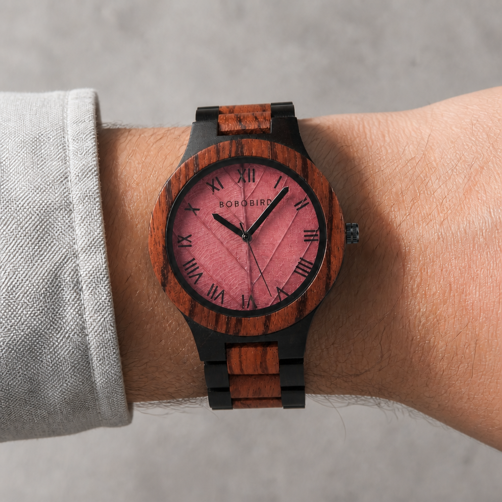 Montre en bois artisanale portée au poignet, cadran feuille rose sur santal
