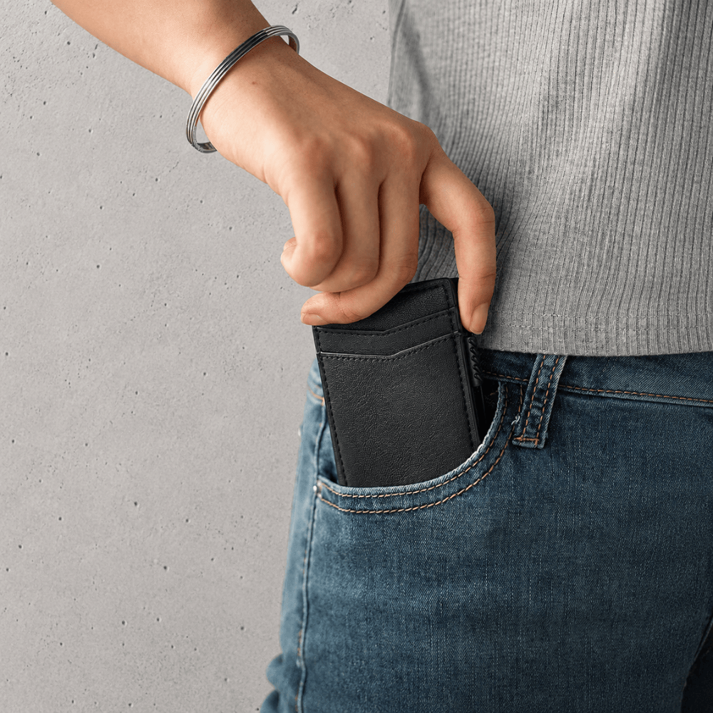 Porte-cartes aluminium noir glissé dans une poche de jean
