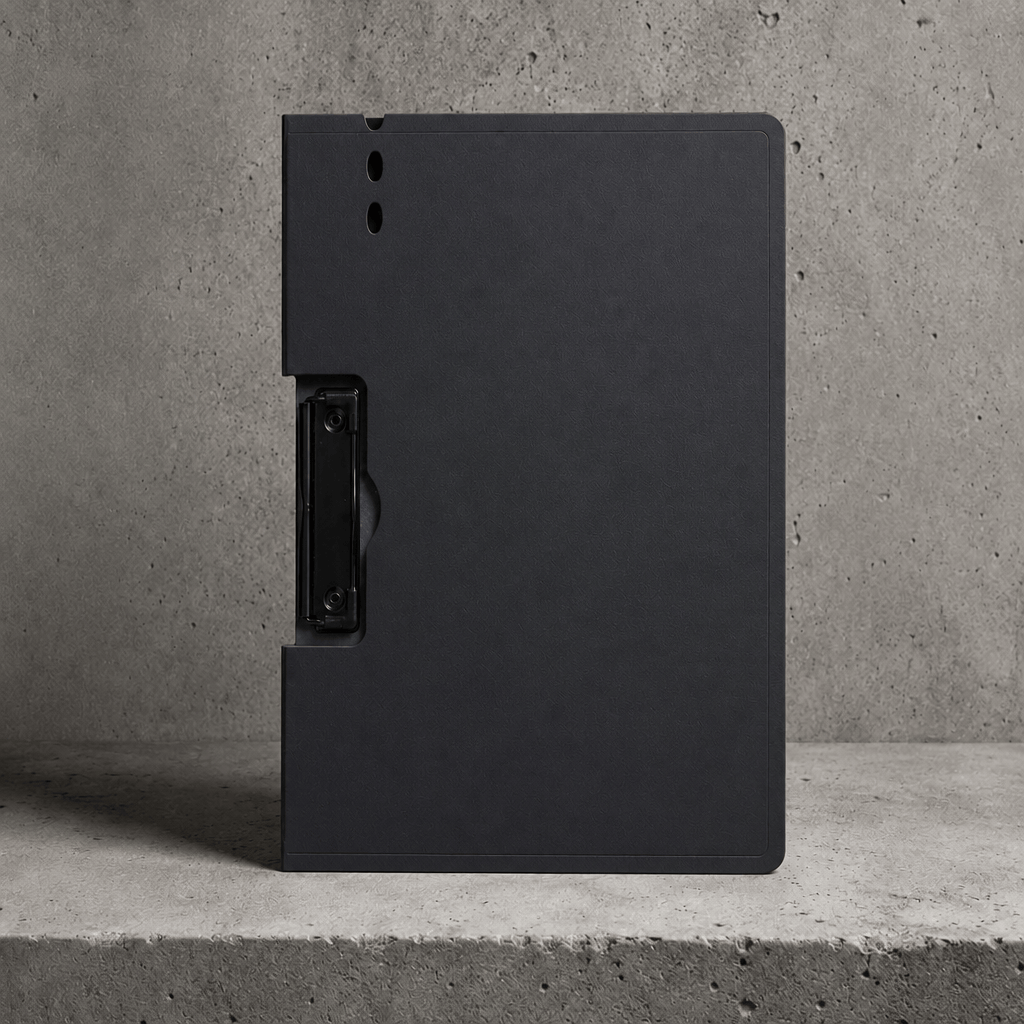 Porte-document à pince A4 noir avec couverture rabattable, fermé, posé sur béton