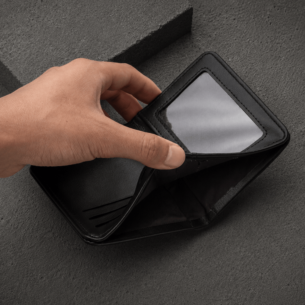 Volet id transparent souleve du portefeuille compact homme noir revelant les logements caches