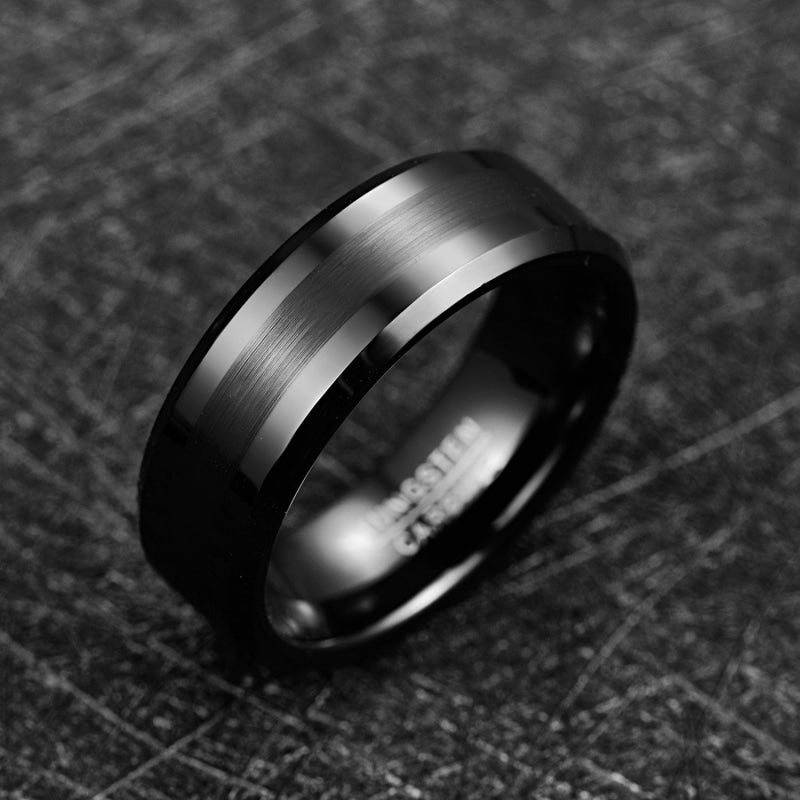 Bague noire homme en tungstène posée sur un fond sombre texturé