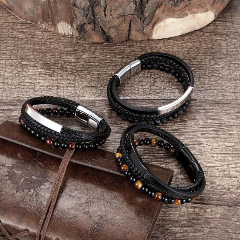 Trois bracelets homme en cuir et perles de pierre posés sur un carnet en cuir