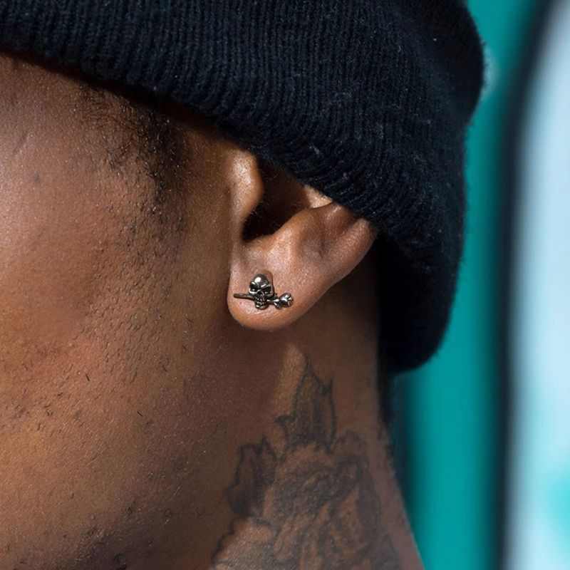 Boucle d’oreille homme crâne avec rose en acier inoxydable portée à l’oreille – vue rapprochée
