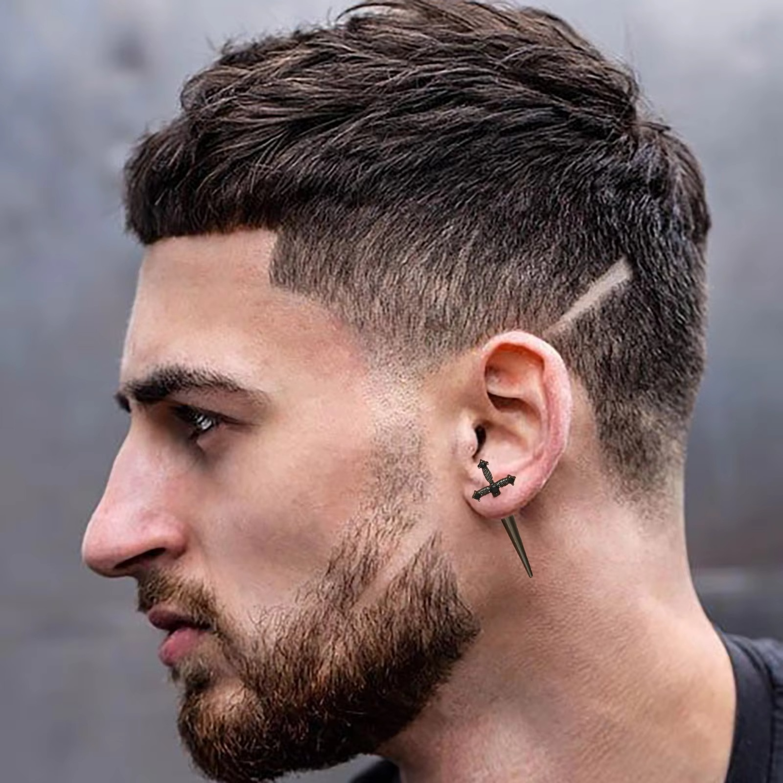 Boucle d'oreille épée en alliage de métaux portée par un homme, style gothique et audacieux.