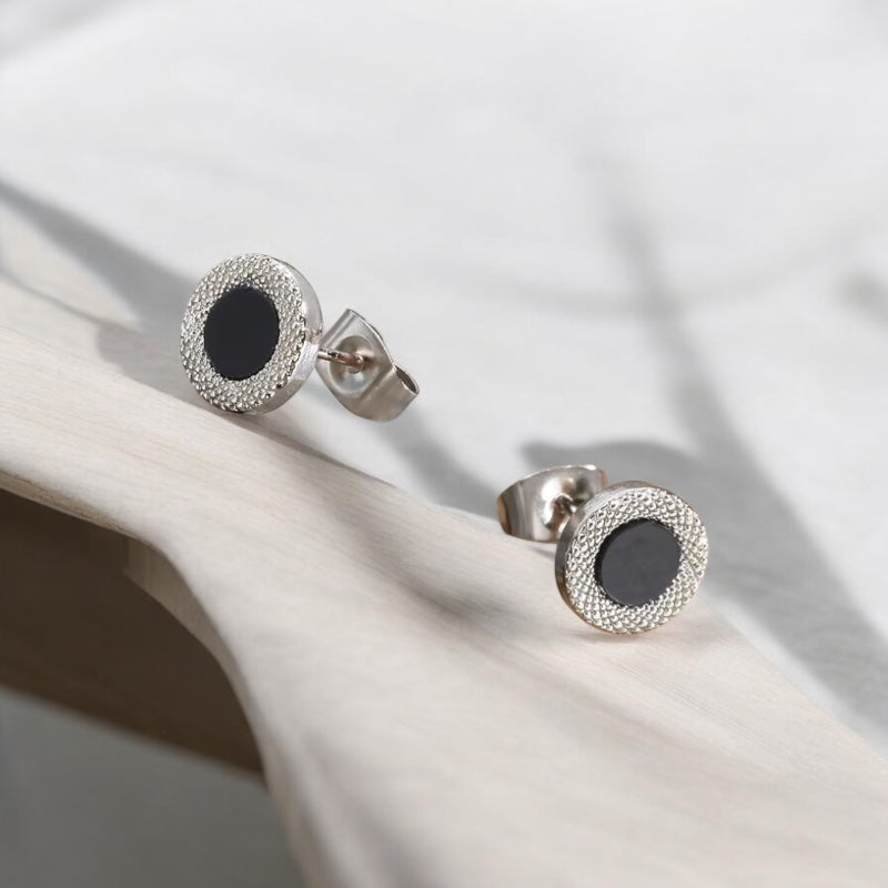 Boucles d’oreilles clous pour homme en acier argenté avec motif circulaire noir, posées 
